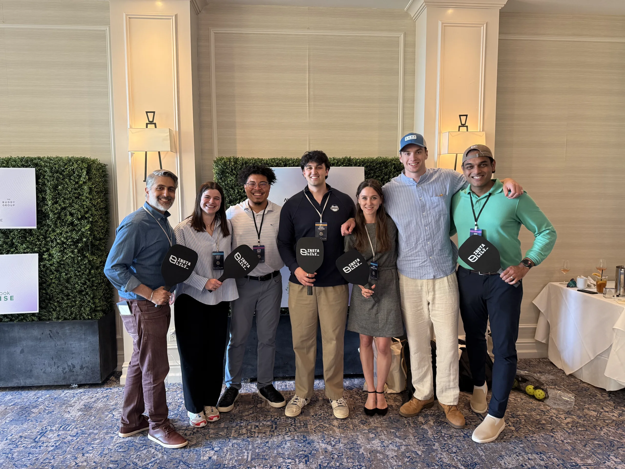 The InstaLILY team together at an offsite event, holding InstaLILY paddles