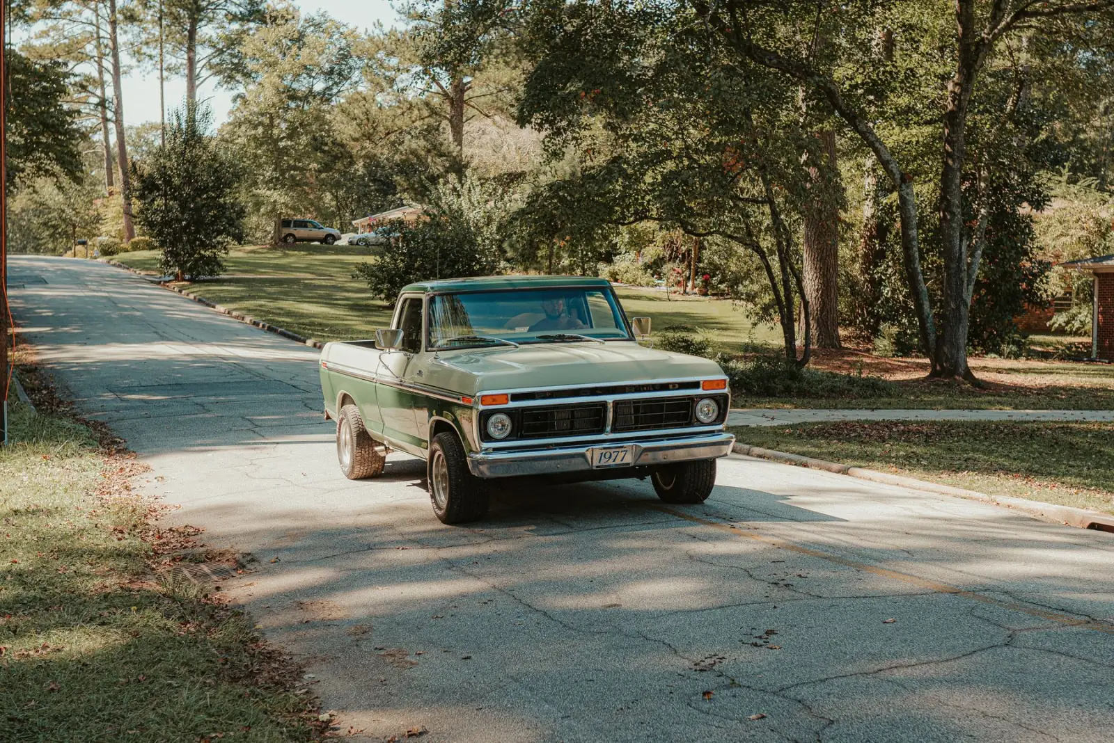 A pickup truck on a tree-lined road.